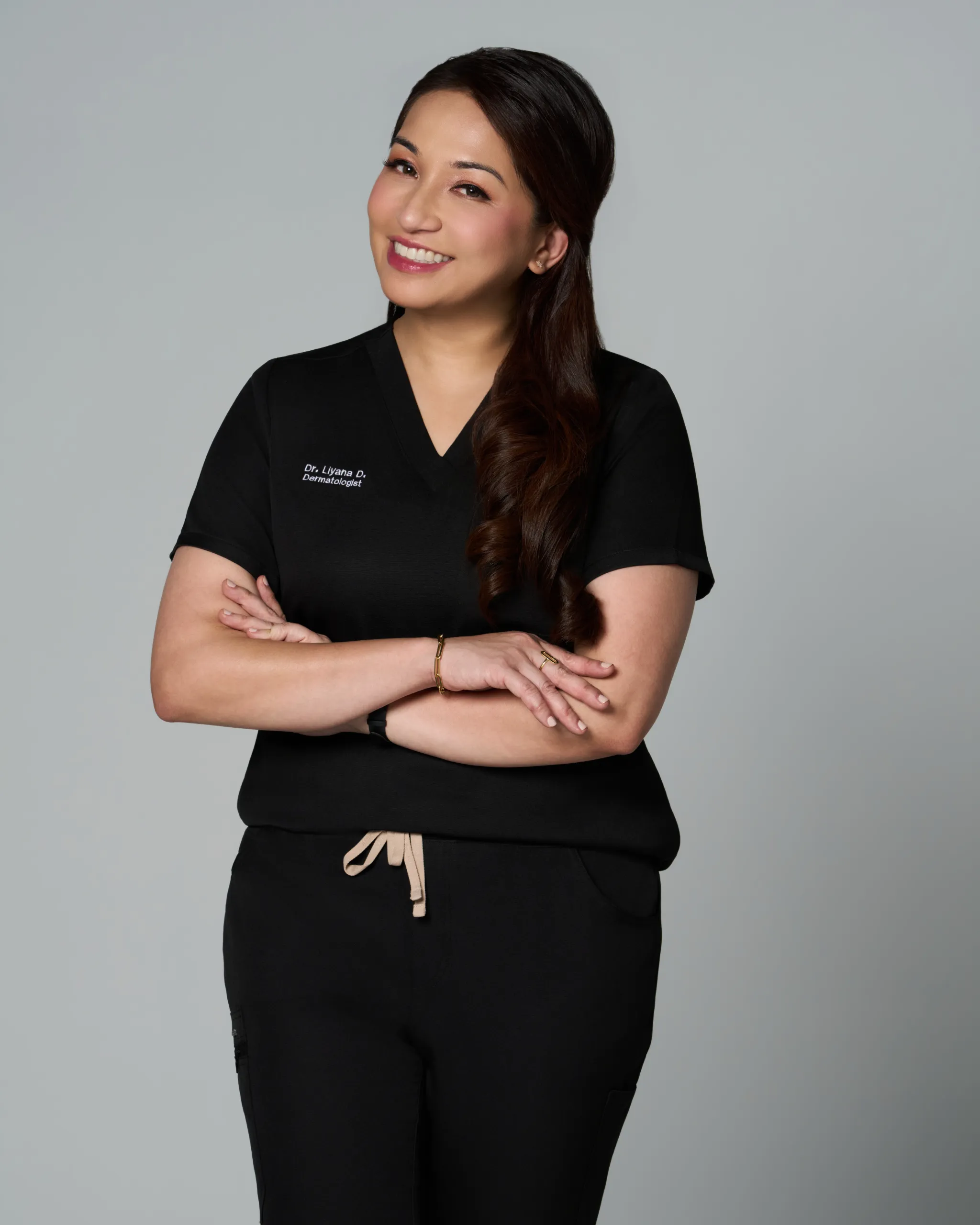A skincare specialist posing confidently in a black outfit.