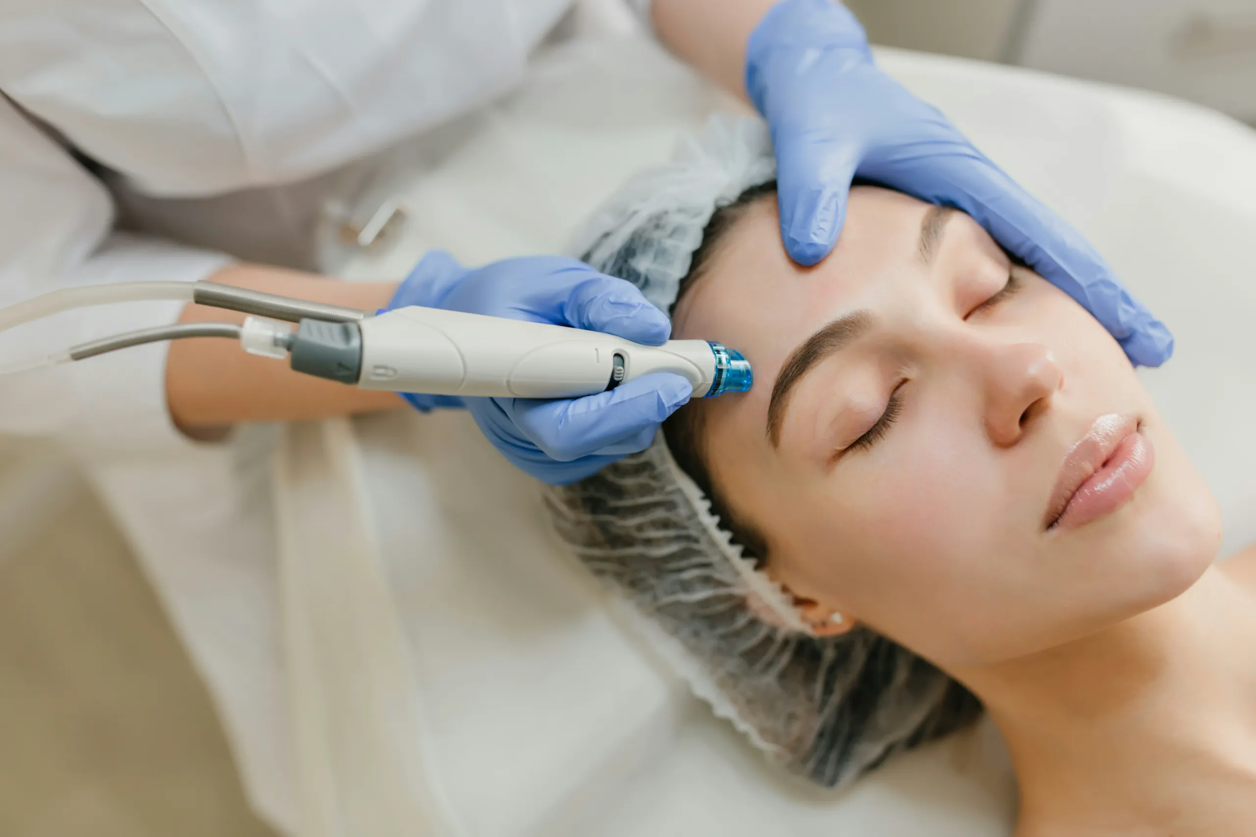 A close-up of a woman receiving a facial treatment with a device.