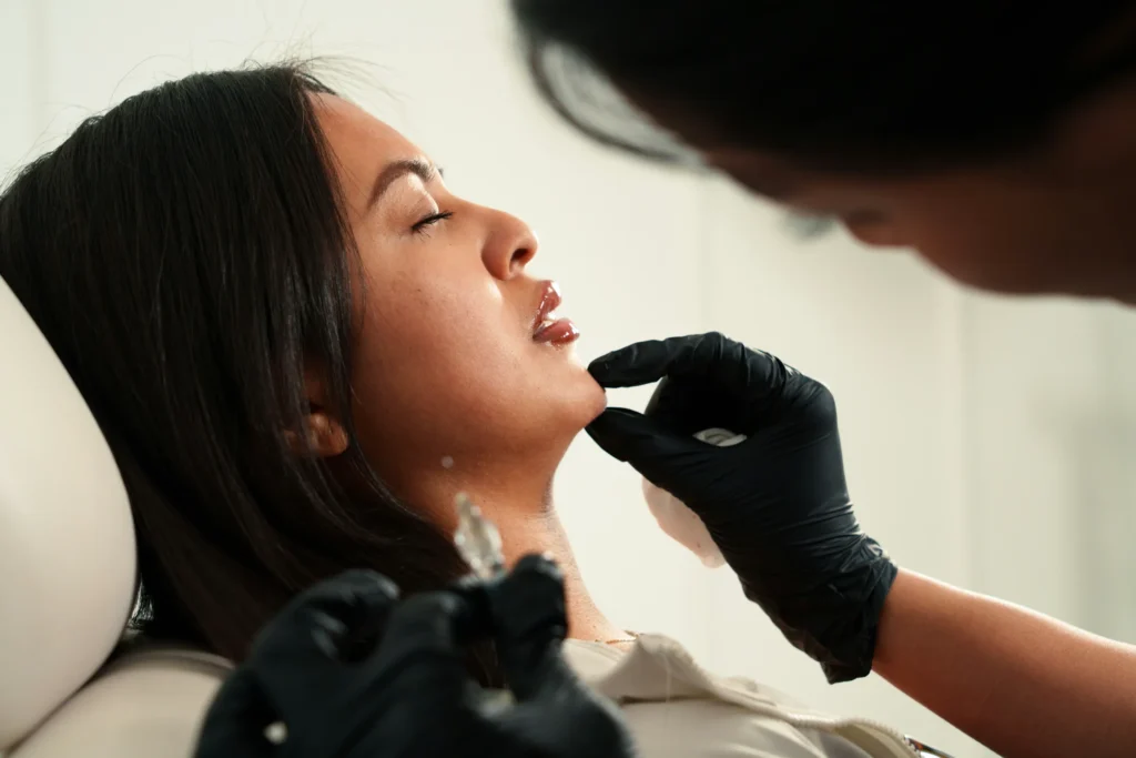 A woman receiving a skincare treatment in a clinical setting.